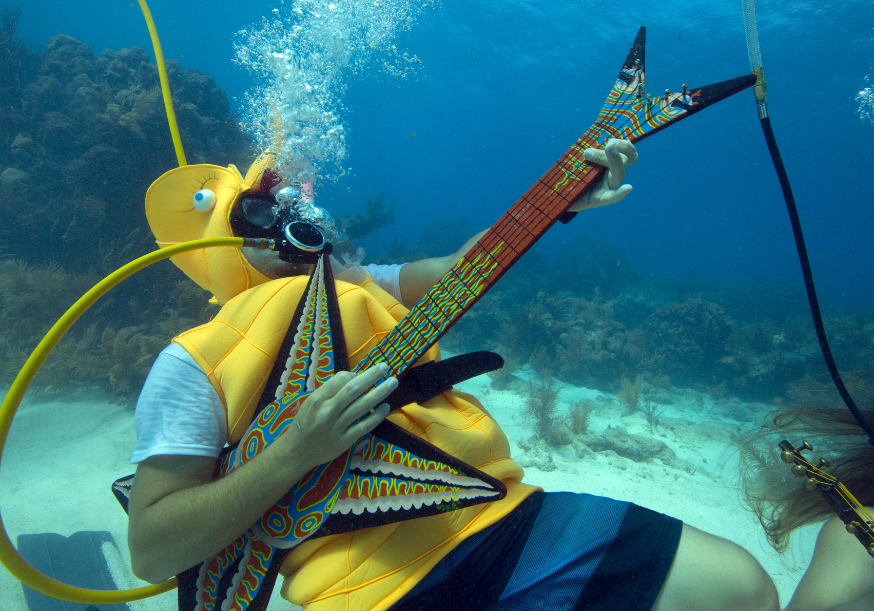 In this photo provided by the Florida Keys News Bureau, Jeff Wright, costumed as a seahorse, rocks with a fake guitar, Saturday, July 11, 2015, during the Underwater Music Festival in the Florida Keys National Marine Sanctuary off Big Pine Key, Fla. The annual event attracted hundreds of divers and snorkelers who listened to a local radio station's four-hour broadcast piped beneath the sea via underwater speakers, featuring music programmed for the subsea listening experience as well as coral reef conservation messages. (Bob Care/Florida Keys News Bureau via AP)