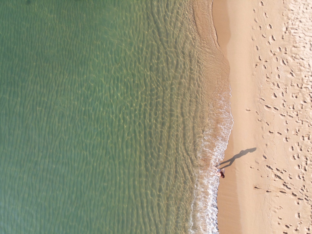 A aerial view of a woman enjoying the waves of Bogatell Beach, one of the best beaches in Barcelona