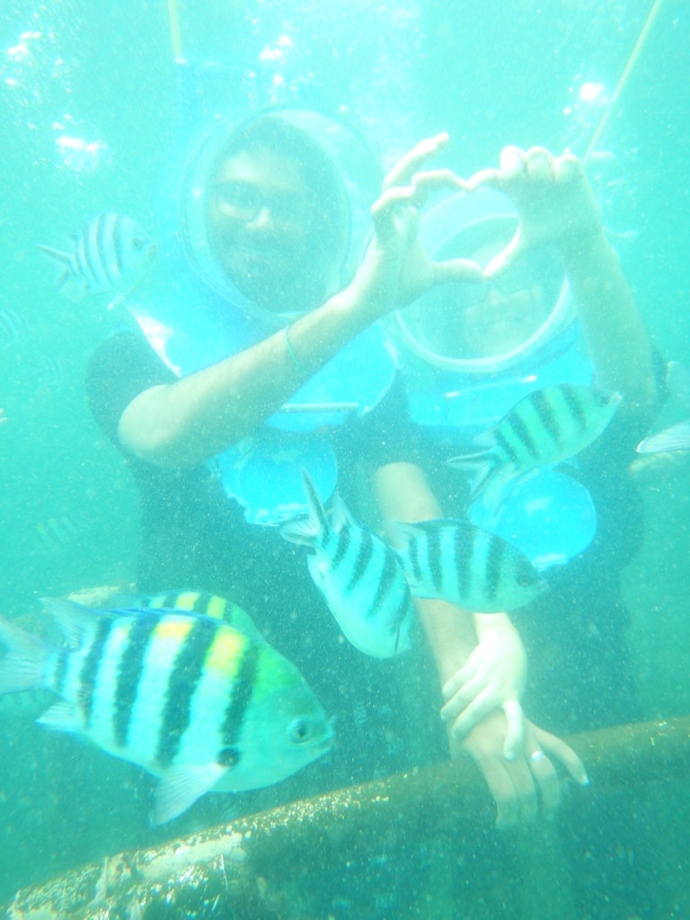 A couple showing the symbol of love during sea walking activity