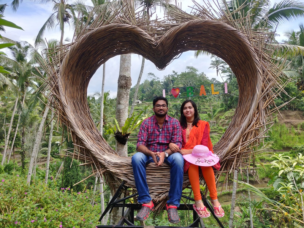 A couple posing with I love Bali sign as the background on their first international trip