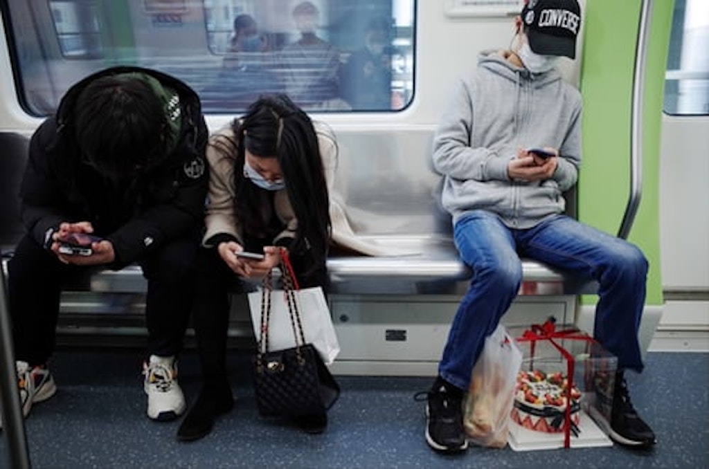 n a metro hunched over their mobile phones.
