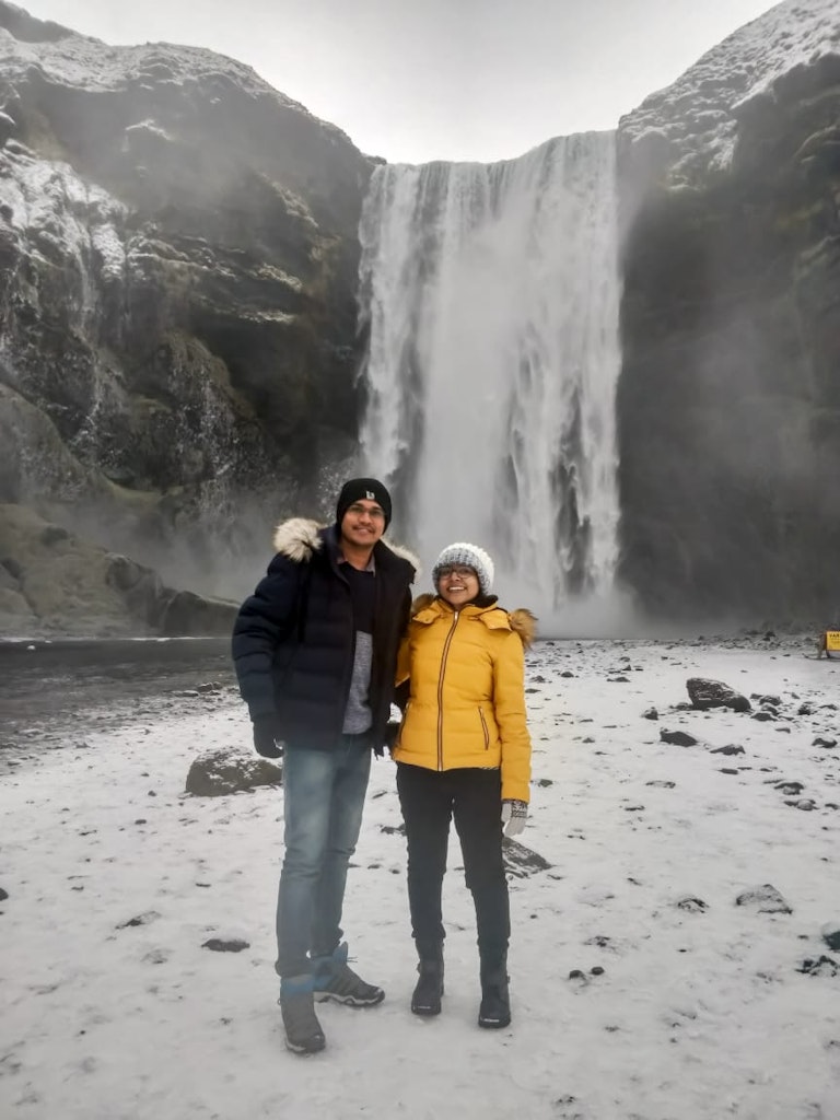 A couple picture with waterfalls as the background on their honeymoon to Iceland