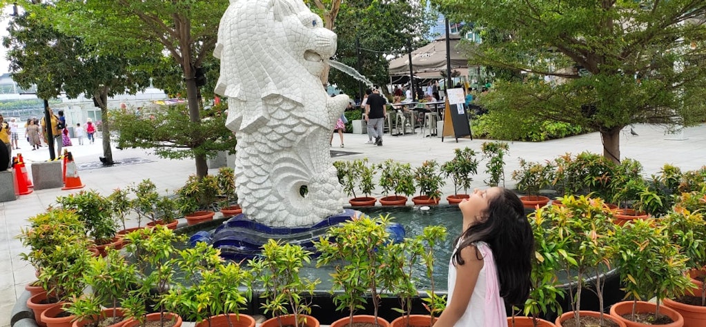 My daughter posing with the lion during our family vacation to Singapore