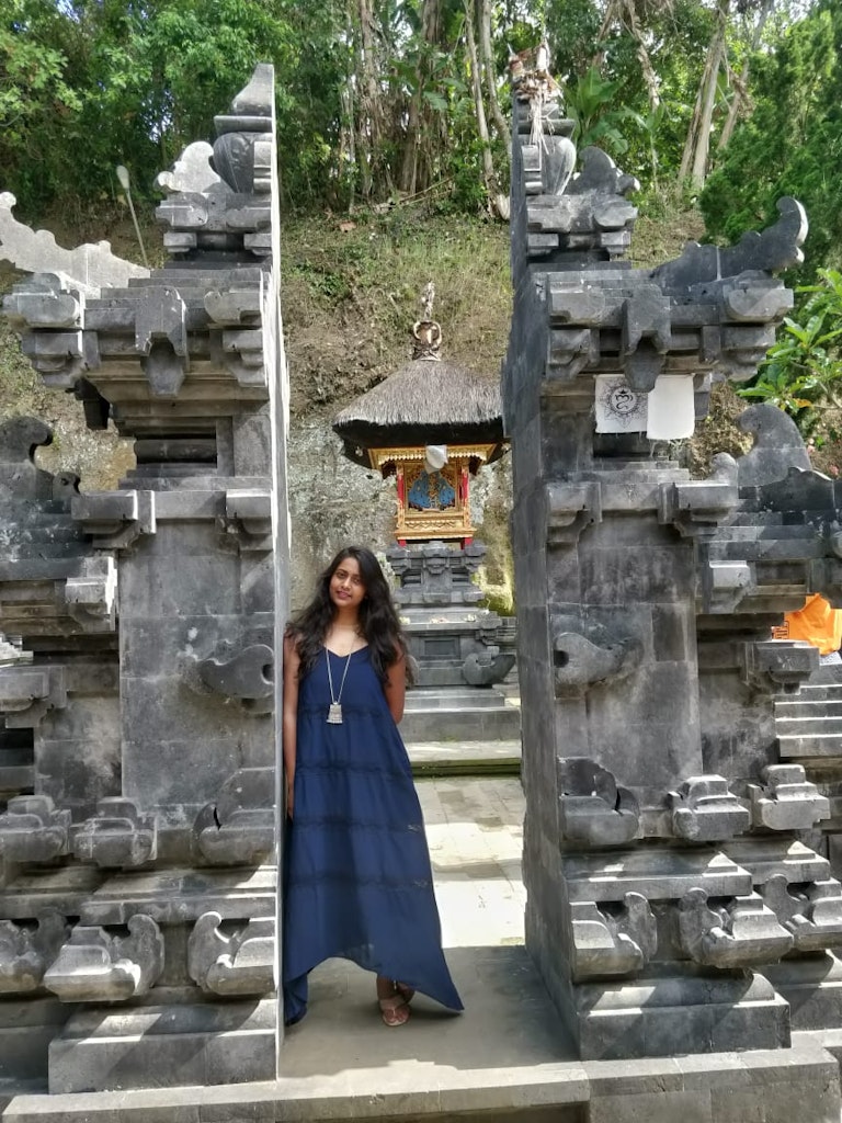 A picture of a lady standing in front of a temple