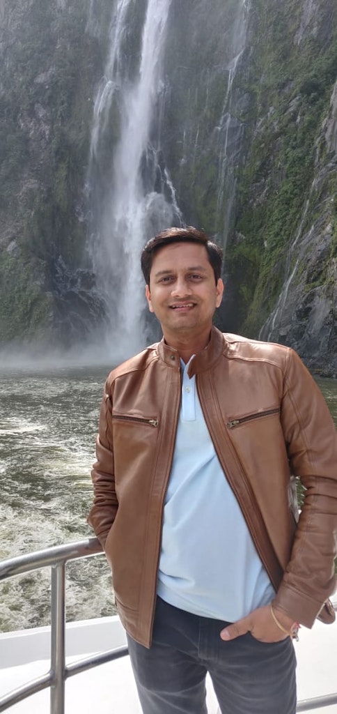 A man posing for a picture with waterfalls as the background