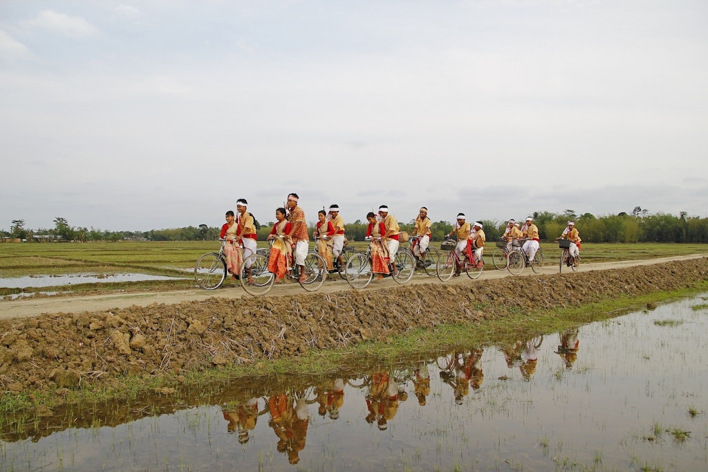 A group of people riding in bicylces in traditional clothes in one of the festivals of Assam